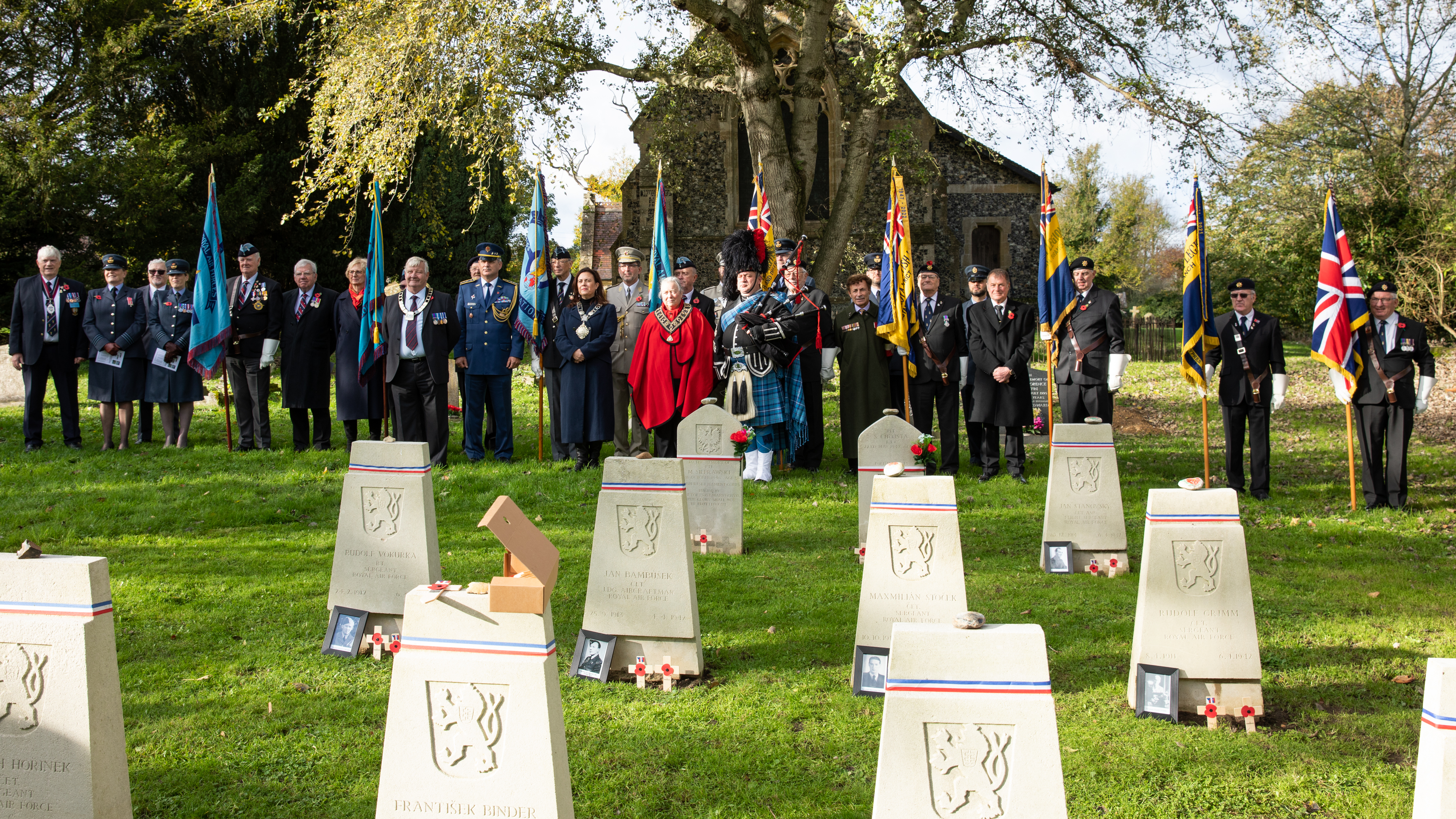 Image shows RAF aviators standing by gravestones during Remembrance Service.